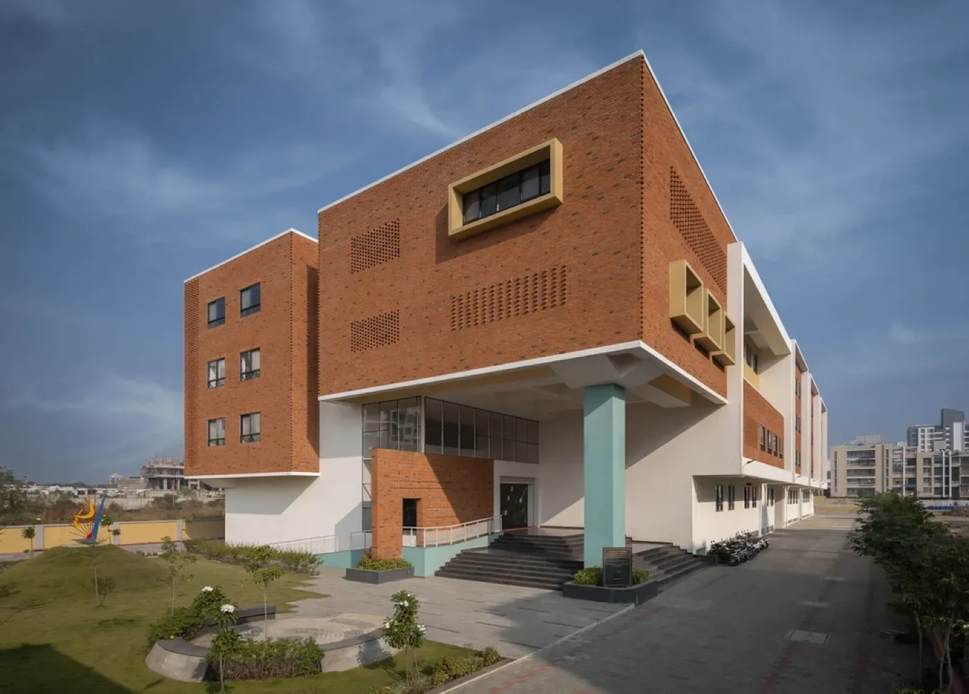 Modern Indian home facade featuring textured terracotta brick wall cladding, glass windows, wooden accents, and landscaped greenery.