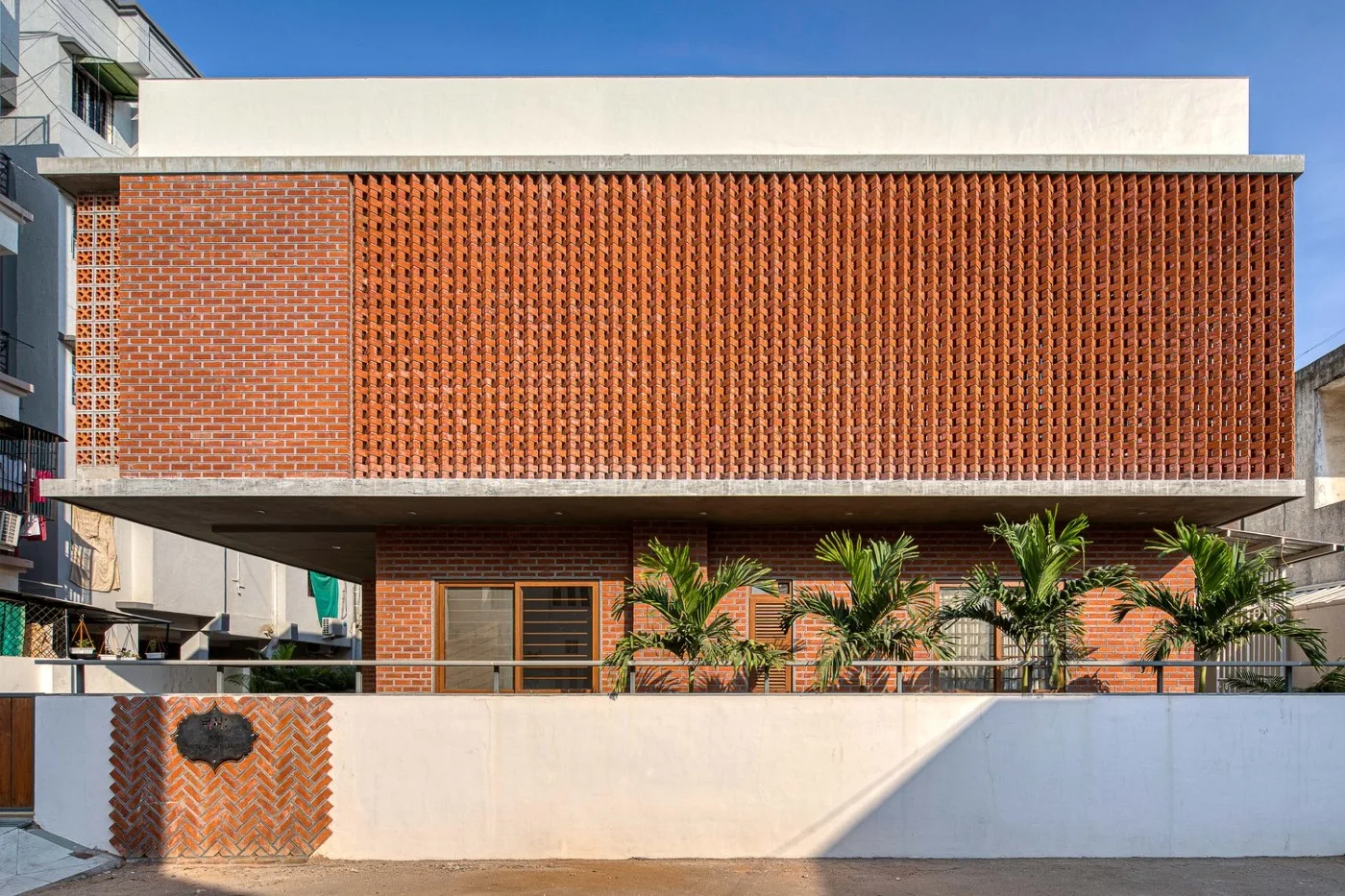 Contemporary Indian home exterior combining red brick cladding with smooth cream plaster walls.